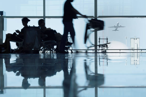 Silhouetted passengers waiting or delayed at an airport terminal in Barcelona, Spain stock photo