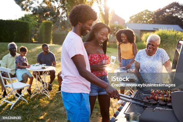 Couple Grilling At A Black Multi Generation Family Barbecue Stock Photo - Download Image Now