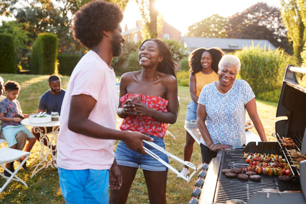 paar lachen om een multi-generatie familie barbecue - gegrild fotos stockfoto's en -beelden