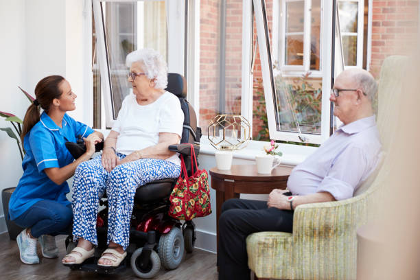 mężczyźni i kobiety mieszkańcy siedzą na krześle i rozmawiają z pielęgniarką w domu spokojnej starości - one person lifestyles 80 plus years indoors zdjęcia i obrazy z banku zdjęć