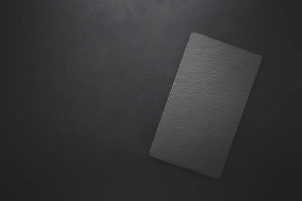 istock Top view on rectangle black slate plate on rustic dark background. Copy space. Toned 1045382462