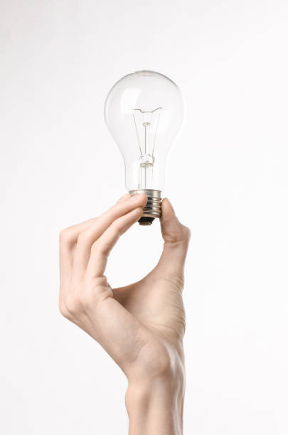 istock Energy consumption and energy saving topic: human hand holding a light bulb on a white background in studio 1045383568