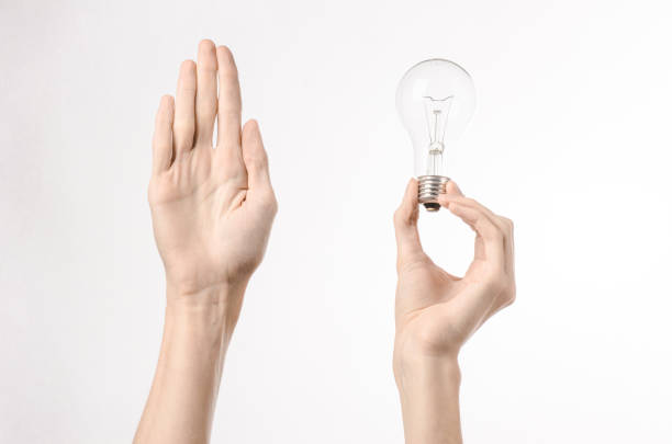 istock Energy consumption and energy saving topic: human hand holding a light bulb on a white background in studio 1045384004