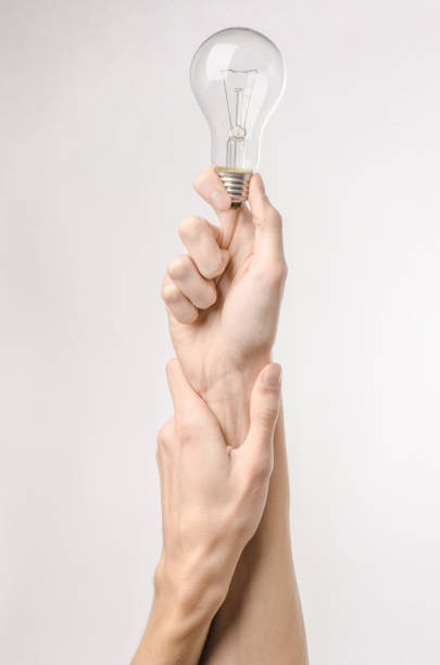 istock Energy consumption and energy saving topic: human hand holding a light bulb on a white background in studio 1045386142