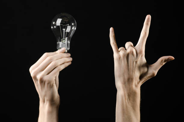 istock Energy consumption and energy saving topic: human hand holding a light bulb on black background in studio 1045386874