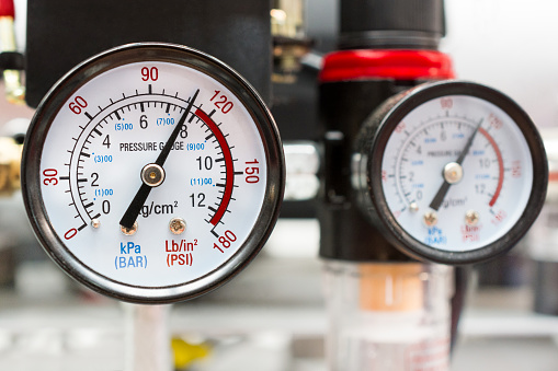 Two industrial manometers show almost critical pressure on the pump.