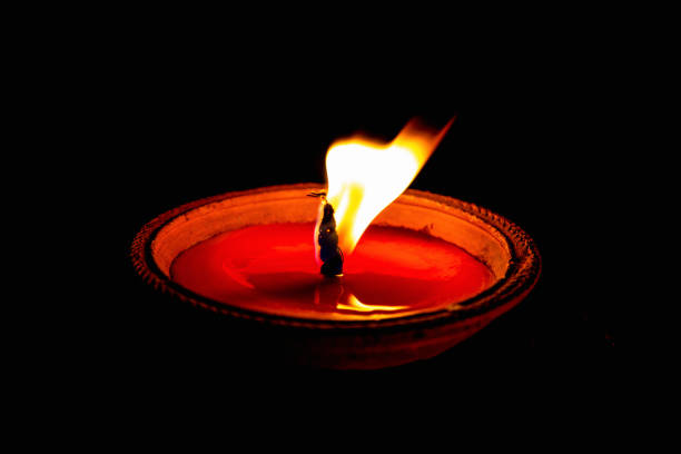 Burning wax candle in small cup isolated on dark background.