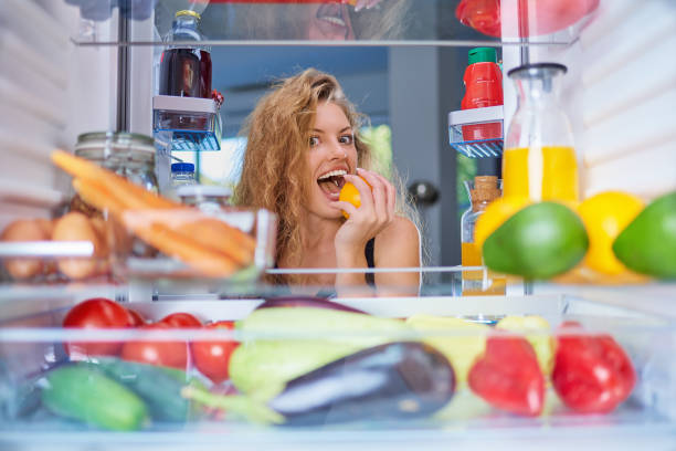 istock Woman biting fruit in front of fridge. 1045408928