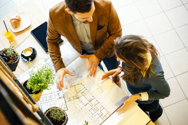 istock Two young architects discussing building plans during a meeting in a modern cafe. High angle view 1045409180
