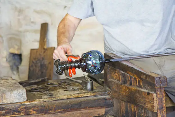 Photo of Glass worker makes glass sculptures in glass factory in Murano, Venice, Italy