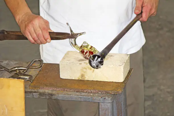 Photo of Glass worker makes glass sculptures in glass factory in Murano, Venice, Italy