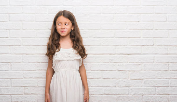 istock Young hispanic kid over white brick wall smiling looking side and staring away thinking. 1045413654