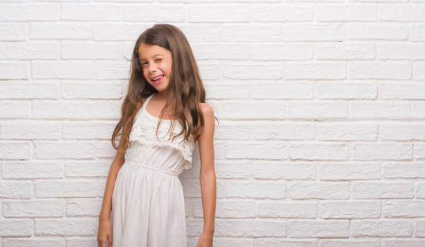 istock Young hispanic kid over white brick wall winking looking at the camera 1045414190