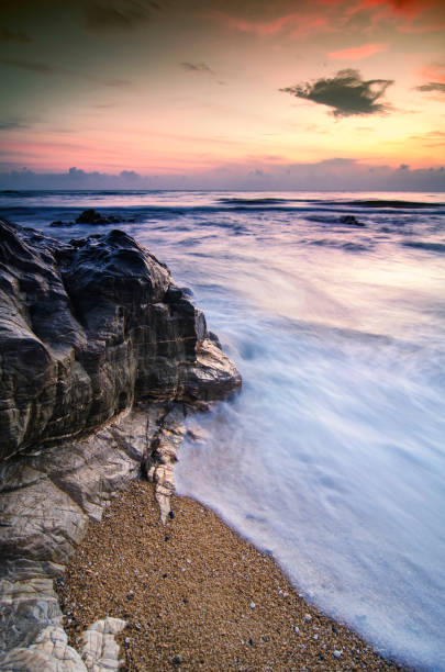istock stunning sunset sunrise  scenery with unique shape rock formation and waves splashing. soft focus due to long exposure shot 1045419888