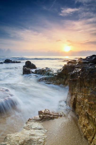 istock stunning sunset sunrise  scenery with unique shape rock formation and waves splashing. soft focus due to long exposure shot 1045419932