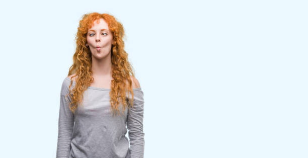 istock Young redhead woman making fish face with lips, crazy and comical gesture. Funny expression. 1045421746