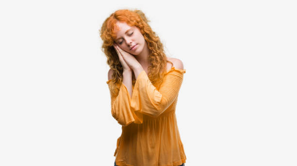 istock Young redhead woman sleeping tired dreaming and posing with hands together while smiling with closed eyes. 1045425672