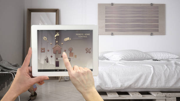 istock Smart remote home control system on a digital tablet. Device with app icons. Minimalist modern bedroom in the background, architecture interior design 1045425844