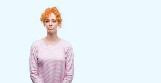 istock Young redhead woman with serious expression on face. Simple and natural looking at the camera. 1045427470