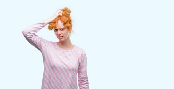 istock Young redhead woman confuse and wonder about question. Uncertain with doubt, thinking with hand on head. Pensive concept. 1045427640