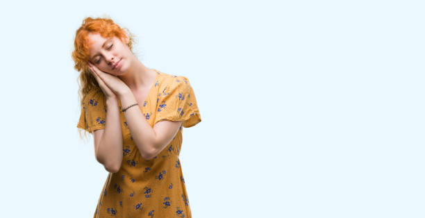 istock Young redhead woman sleeping tired dreaming and posing with hands together while smiling with closed eyes. 1045431866