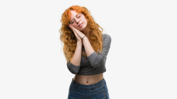 istock Young redhead woman sleeping tired dreaming and posing with hands together while smiling with closed eyes. 1045433686