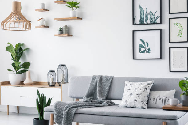 istock Pillows and blanket on grey couch in white scandinavian loft interior with plants and gallery. Real photo 1045435688