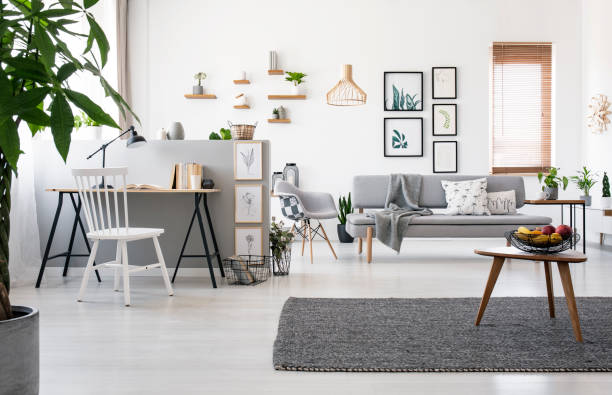 istock Wooden table on grey carpet in spacious apartment interior with workspace and posters. Real photo 1045435786