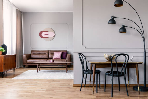 istock Black chairs at table next to lamp in white apartment interior with poster above sofa. Real photo 1045439224