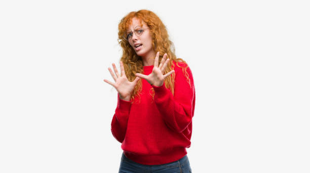 istock Young redhead woman wearing red sweater afraid and terrified with fear expression stop gesture with hands, shouting in shock. Panic concept. 1045439730