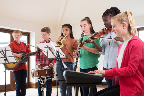 High School Students Playing In School Orchestra Together High School Students Playing In School Orchestra Together performance group stock pictures, royalty-free photos & images