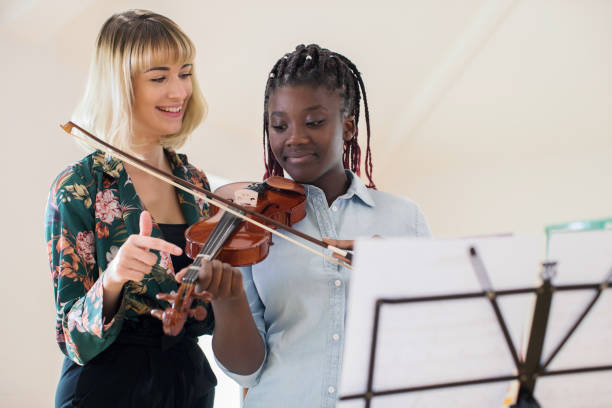 tutor lehre high-school-schüler im musikunterricht geige spielen - practicing music violin women stock-fotos und bilder