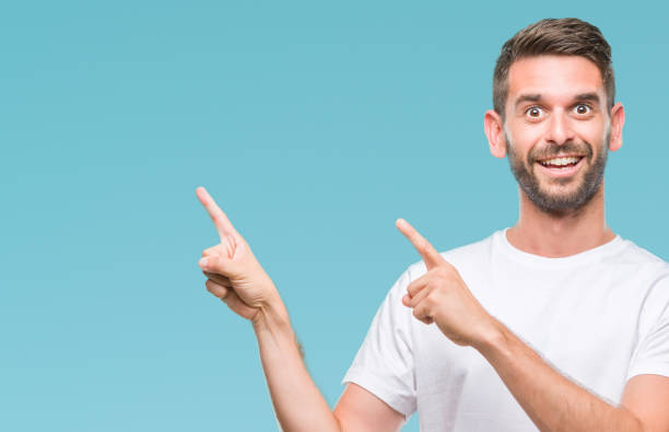 istock Young handsome man over isolated background smiling and looking at the camera pointing with two hands and fingers to the side. 1045447654