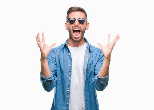 istock Young handsome man wearing sunglasses over isolated background celebrating mad and crazy for success with arms raised and closed eyes screaming excited. Winner concept 1045447714