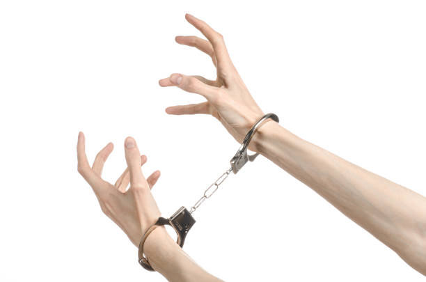 istock Prison and convicted topic: man hands with handcuffs isolated on white background in studio, put handcuffs on killer 1045449130