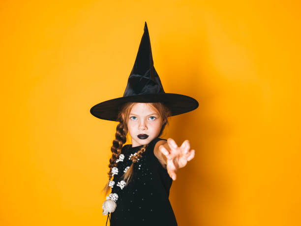 istock young halloween witch on orange background with black hat 1045451320