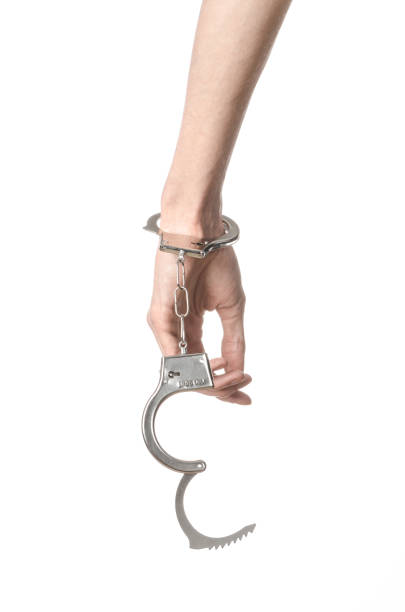 istock Prison and convicted topic: man hands with handcuffs isolated on white background in studio, put handcuffs on killer 1045453458