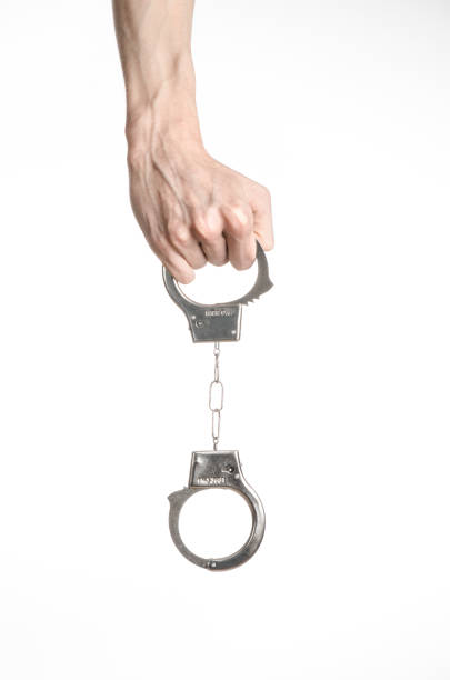 istock Prison and convicted topic: man hands with handcuffs isolated on white background in studio, put handcuffs on killer 1045453474
