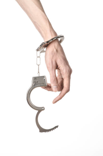 istock Prison and convicted topic: man hands with handcuffs isolated on white background in studio, put handcuffs on killer 1045453502