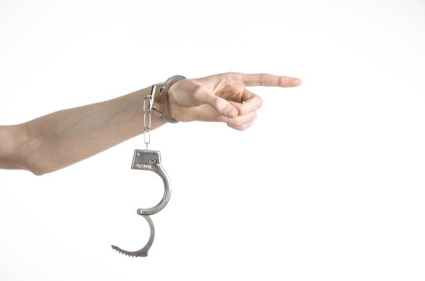 istock Prison and convicted topic: man hands with handcuffs isolated on white background in studio, put handcuffs on killer 1045453584