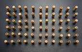 A lot of wooden pegs standing vertically on a black background.