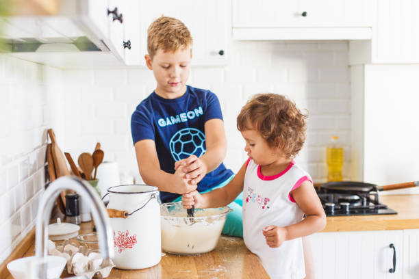 istock Brother and sister preparing dough for pancakes at the kitchen. 1045454228