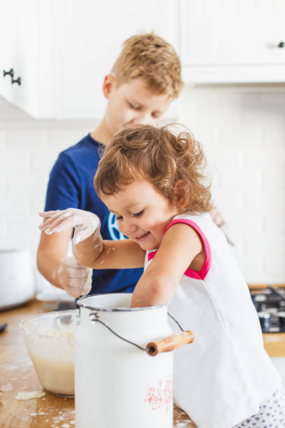 istock Brother and sister preparing dough for pancakes at the kitchen. 1045454304