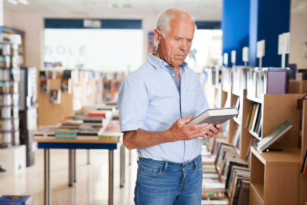 istock Older man visitor looking for necessary book in bookshop 1045454868