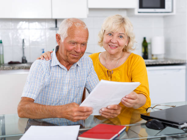 istock Happy mature couple with documents sitting at table in home 1045455338