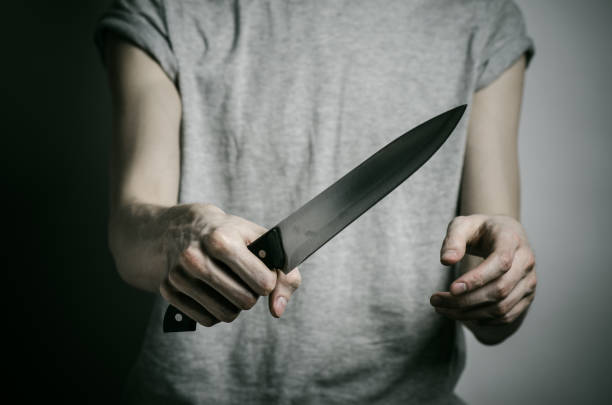 istock Murder and Halloween theme: a man holding a knife on a gray background 1045457496