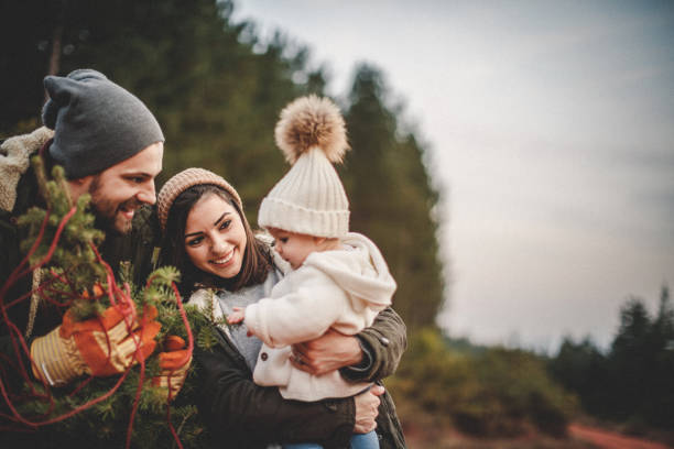 Happy parents with their daughter picking out a Christmas tree Happy parents with their daughter picking out a Christmas tree plantation photos stock pictures, royalty-free photos & images