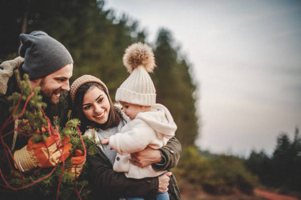 happy parents with their daughter picking out a christmas tree - family winter walking fun imagens e fotografias de stock