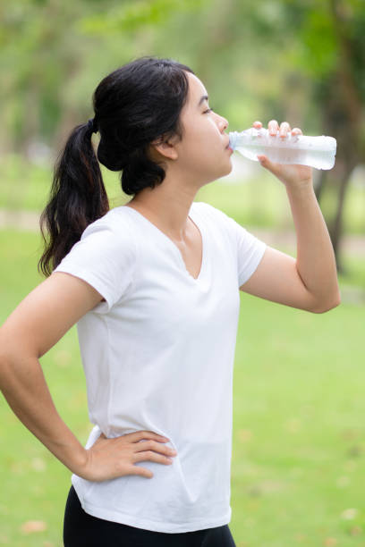 istock Young woman drinking water form a bottle at park. 1045461968