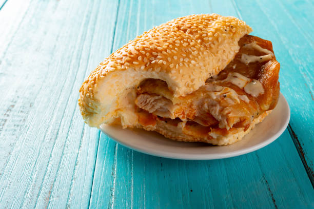 side view studio shot of bread with chicken with some bites close up